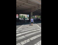 Guy crossing the crosswalk holding a bike  and a giant wheel