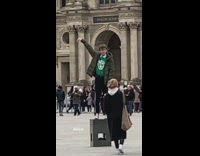 Guy stands on block touches The Louvre pyramid