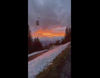 Sunset sky over snowy mountains cable car