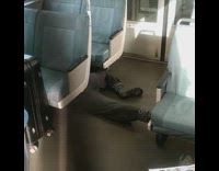 Guy lays on train floor under seats 