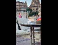 Woman pink dress raises arms while man take pictures behind