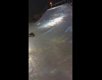 Shirtless guy yellow rollerblades does backflip in falls down half pipe