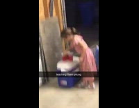 Little girl plays beer bong in garage