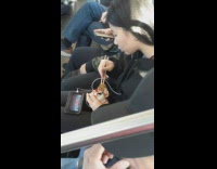 Girl eats small bag of hot cheetos with chopsticks on metro train