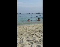 Man shirtless lie down and shows hand at the beach shore
