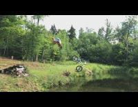 Guy blue shorts jumps off ramp with bike and backflips into lake water