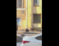 guy sits bench yellow building background