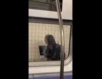 Man charges laptop at subway ceiling outlet