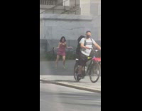 Female dancer performs for video on sidewalk next to big building 