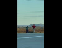 Man gray shirt spread arms pose with a field behind him
