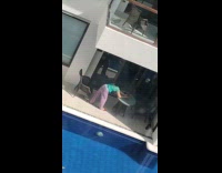 Woman in green and violet outfit tiktok at poolside