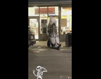 Skeleton dinosaur walks along street at night halloween 