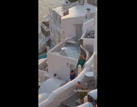 Woman in green dress climb stairs at Santorini