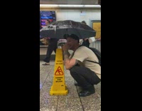 Two guys dance and use umbrella at leaking station 