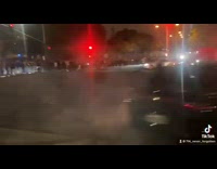 Two cars do donuts middle of crowd