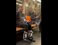 Man rides subway while fixing boots laces