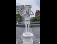 Living statue street performer wears arch on head