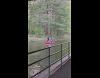 Two people row red kayak in river