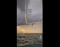 Person in boat looking at massive white super yacht 