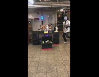 Man plays saxophone with dancing puppets in subway station