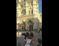 Woman white pants feeds pigeons Notre Dame