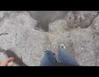 Guy runs across flat grey rocks water