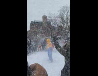 Guy stands in middle of circle of people throwing snowballs at him