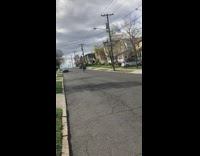 Guy rides bikes downhill on street, jumps off ramp and falls down, bike hits him on the head