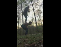 Girl on guys back jumps falls woods 