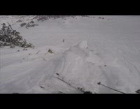 Guy skis off tall cliff and tumbles down hill