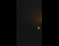 Red lights fluctuate at night behind the trees