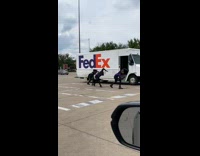 Three FedEx delivery men dance beside truck