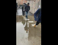 People crossing a flooded sidewalk on sandbags laid as a pathway 
