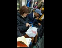 Guy with blue hat trims nose hair with nose hair trimmer on subway