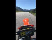 Guy wheelie orange dirt bike road street 