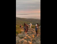 Two girls pose mountain white hat sunset 