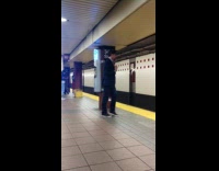 Man in business suit sings out loud to song with earphones in at subway station
