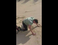Guy running full speed down sand hill loses balance and falls