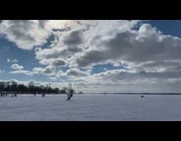 Guy rides board with sail across snow 