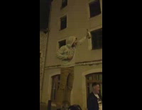 Guy stands on a trash bin, cheers in front of crowd, and drinks bottle of vodka 
