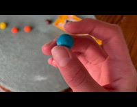 Person holds a round blue MMs chocolate