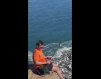 Man orange shirt sit mountain rock selfie 
