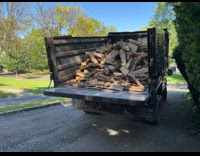 Truck unloads lots of firewood on ground