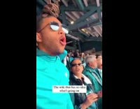 Lady Looks at Man as He Cheers