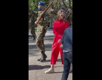 Woman in a red dress poses with soldiers on the march
