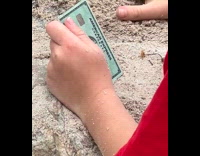 Kid using amex card to play with sand
