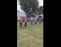 Guy in orange shirt does ramp jump over small fire on mini motorcycle