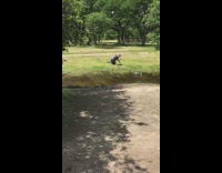 man jumps over stream and slips