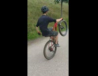 Orange gloves guy rides red bicycle wheelie 