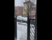 Two guys carrying mattress on sidewalk in snow
